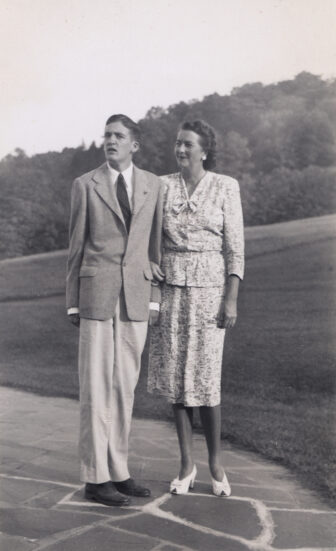 A black and white photo of Serena Merck and her son John standing outside with arms linked